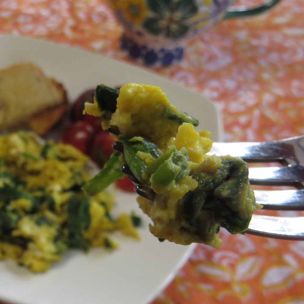 Closeup of bite of Green Eggs (spinach and garlic eggs) on fork.