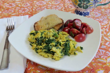 Table setting of Green Eggs (spinach and garlic eggs) with sliced tomatoes and toasted bread.)