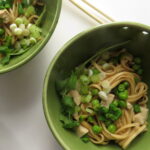 Close-up of bowls of the Cold Noodle Salad with peas, tofu, sliced green onions and cilantro.