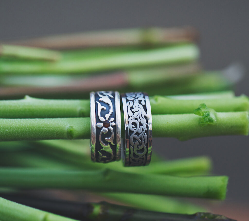Sterling silver celtic wedding bands displayed on end of flower stems.